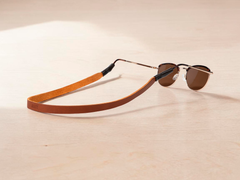 Copper leather sunglass strap monogrammed with initials, attached to a pair of sunglasses