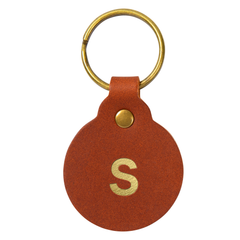 Round tan full-grain leather key fob with gold hardware, stamped with a single initial
