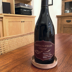 Natural wet-formed leather wine bottle coaster personalized with a monogram, holding a wine bottle